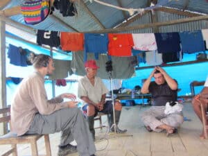 Lukas Kristo recording a Maijuna elder in Peru in a semi-open house.